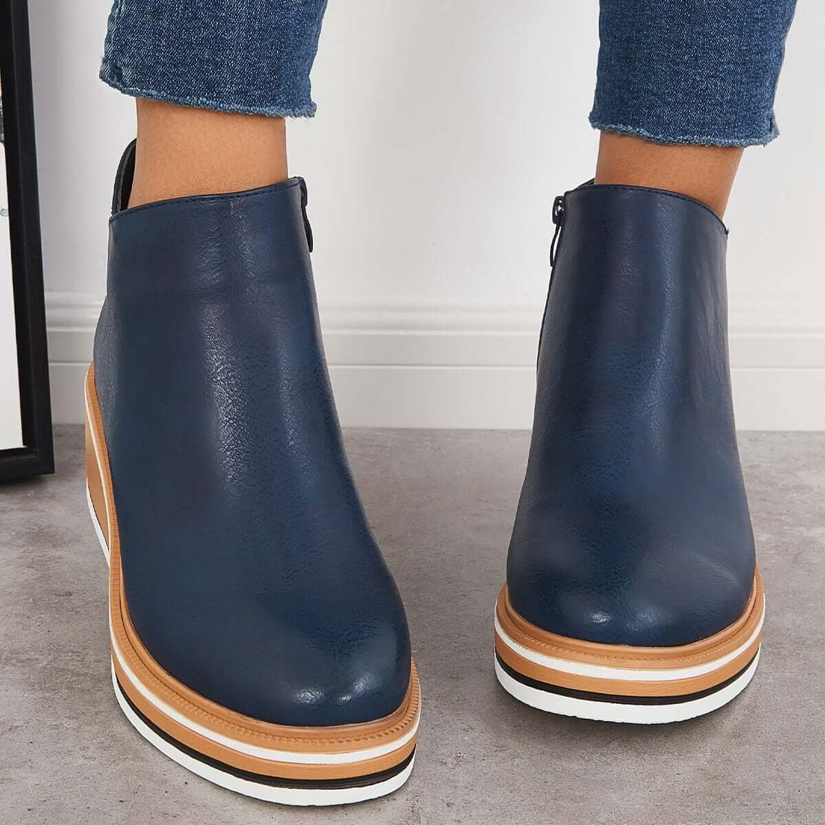 Navy blue ankle boots shown from the front with rounded toes and layered platform soles.