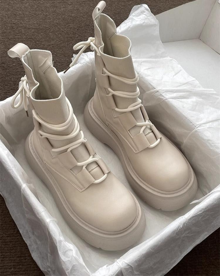 Pair of high-top lace-up platform boots with chunky soles in a neutral tone, displayed on white tissue paper in an open box._0