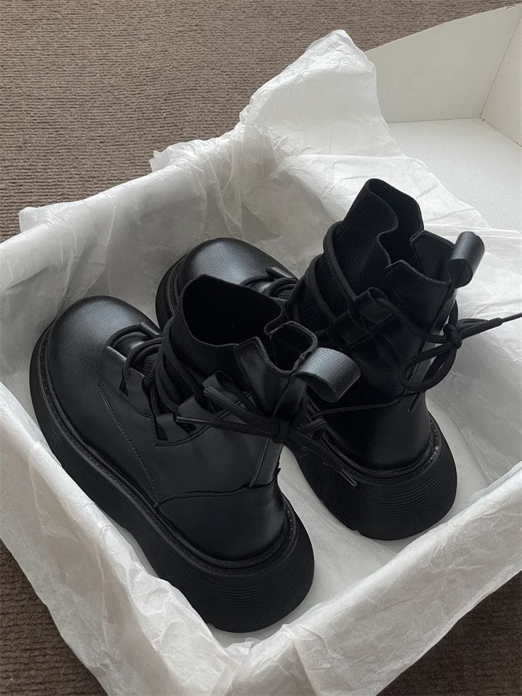 Pair of high-top lace-up platform boots with chunky soles in a neutral tone, displayed on white tissue paper in an open box._4
