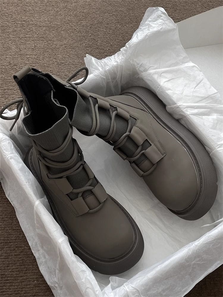 Pair of high-top lace-up platform boots with chunky soles in a neutral tone, displayed on white tissue paper in an open box._6