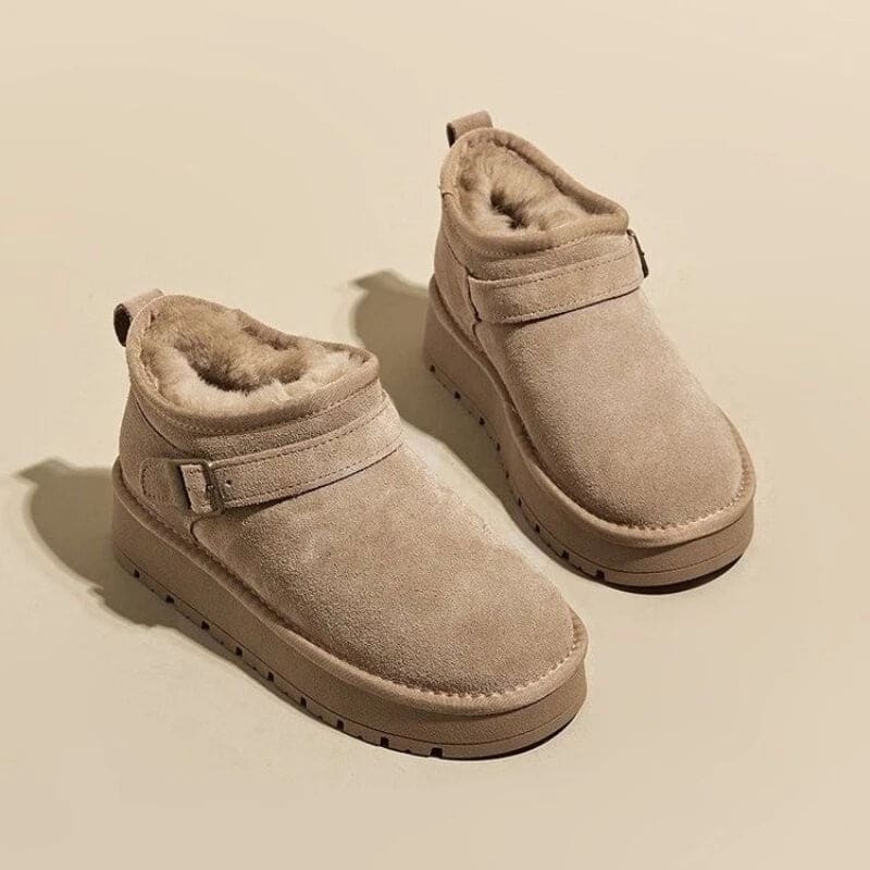 Close-up of a person wearing tan ankle boots with plush lining, buckle detail, and platform sole, paired with gray joggers and neutral socks._12