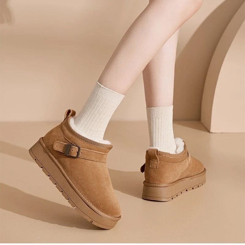 Close-up of a person wearing tan ankle boots with plush lining, buckle detail, and platform sole, paired with gray joggers and neutral socks._14