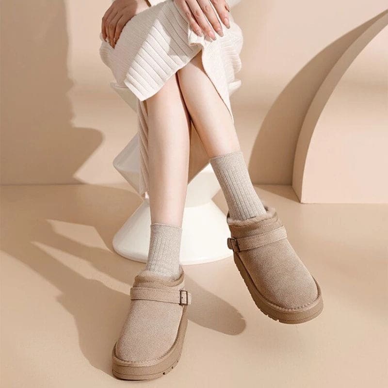Close-up of a person wearing tan ankle boots with plush lining, buckle detail, and platform sole, paired with gray joggers and neutral socks._15