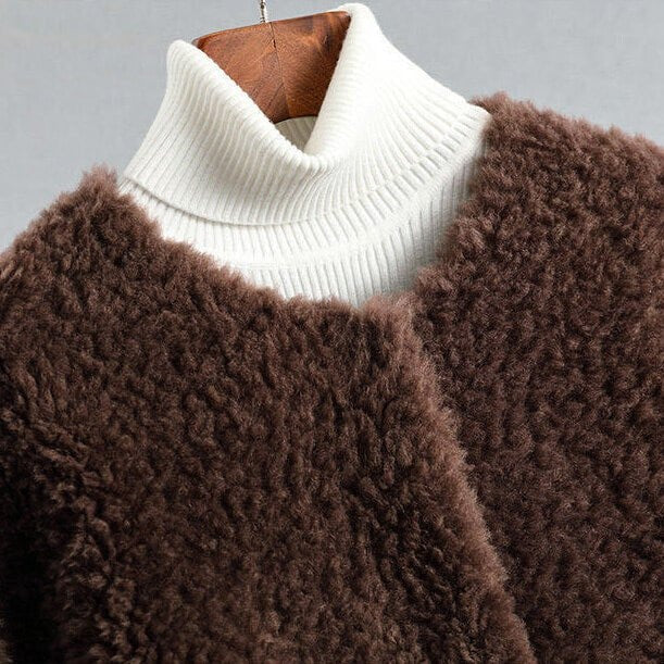 Close-up of the brown plush coat’s textured surface and open front beside a contrasting white ribbed turtleneck collar.
