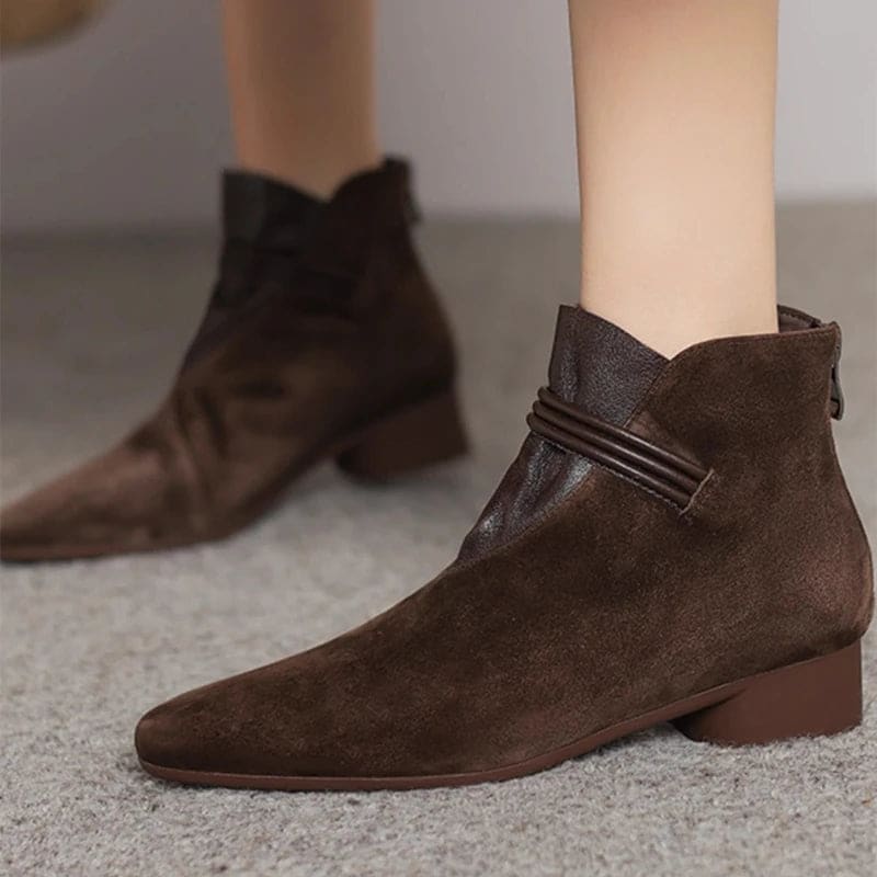 A side view of a pointed toe ankle boot with a decorative strap detail and low block heel._23