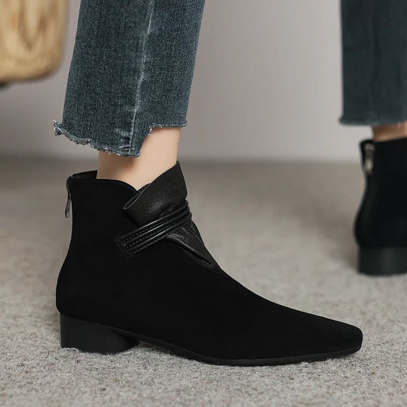 A side view of a pointed toe ankle boot with a decorative strap detail and low block heel._24
