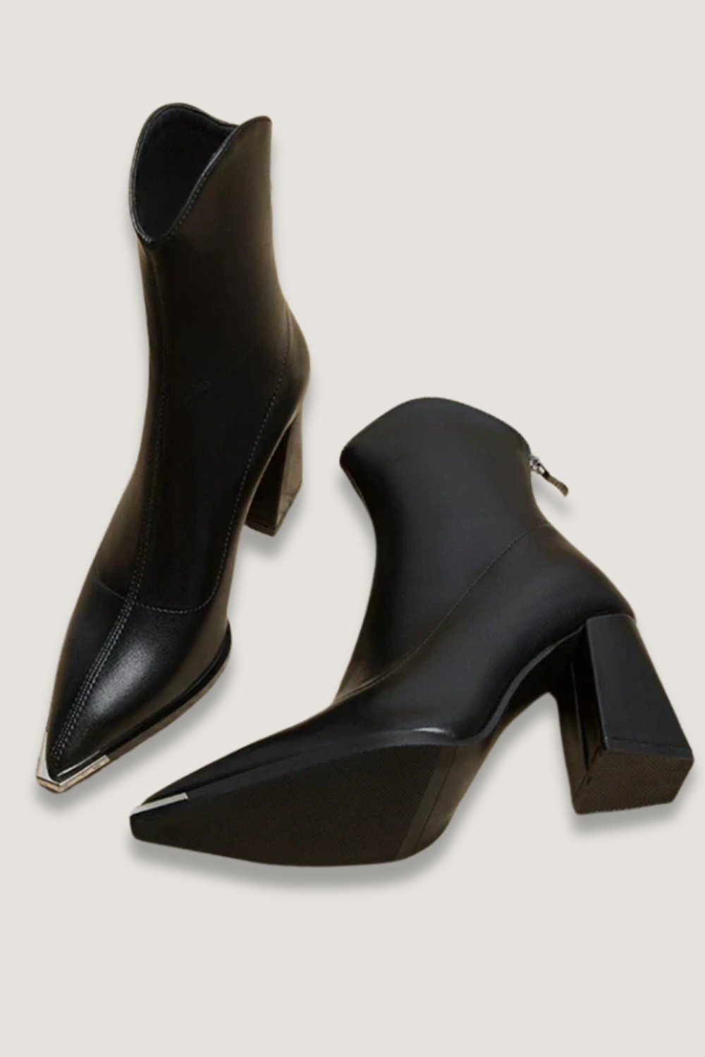 Pair of black pointed-toe ankle boots arranged on a light background, showing the metallic toe tips and chunky block heels.