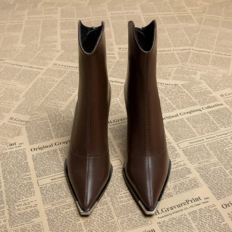Front view of two dark brown pointed-toe ankle boots standing side by side, highlighting their tall shafts and metallic toe tips.