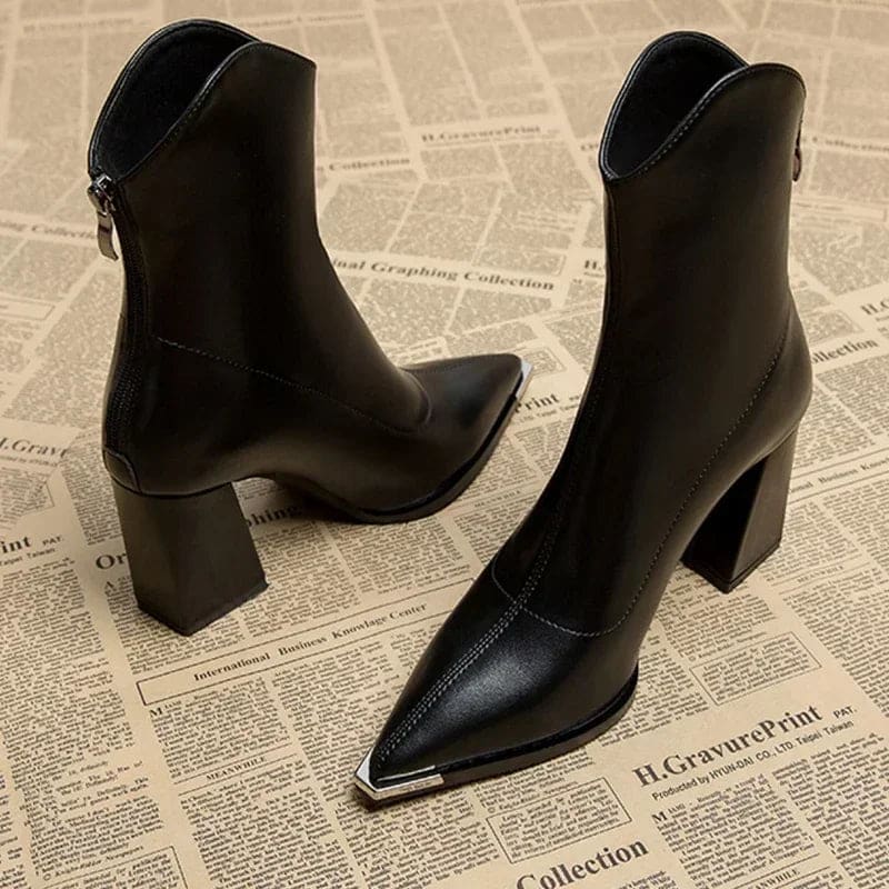 Pair of pointed toe chelsea boots with chrome tip detail and chunky block heel displayed on newspaper background_4