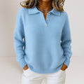 Light blue polo collar sweater with a button placket, long sleeves, and ribbed cuffs and hem, styled with white pants.