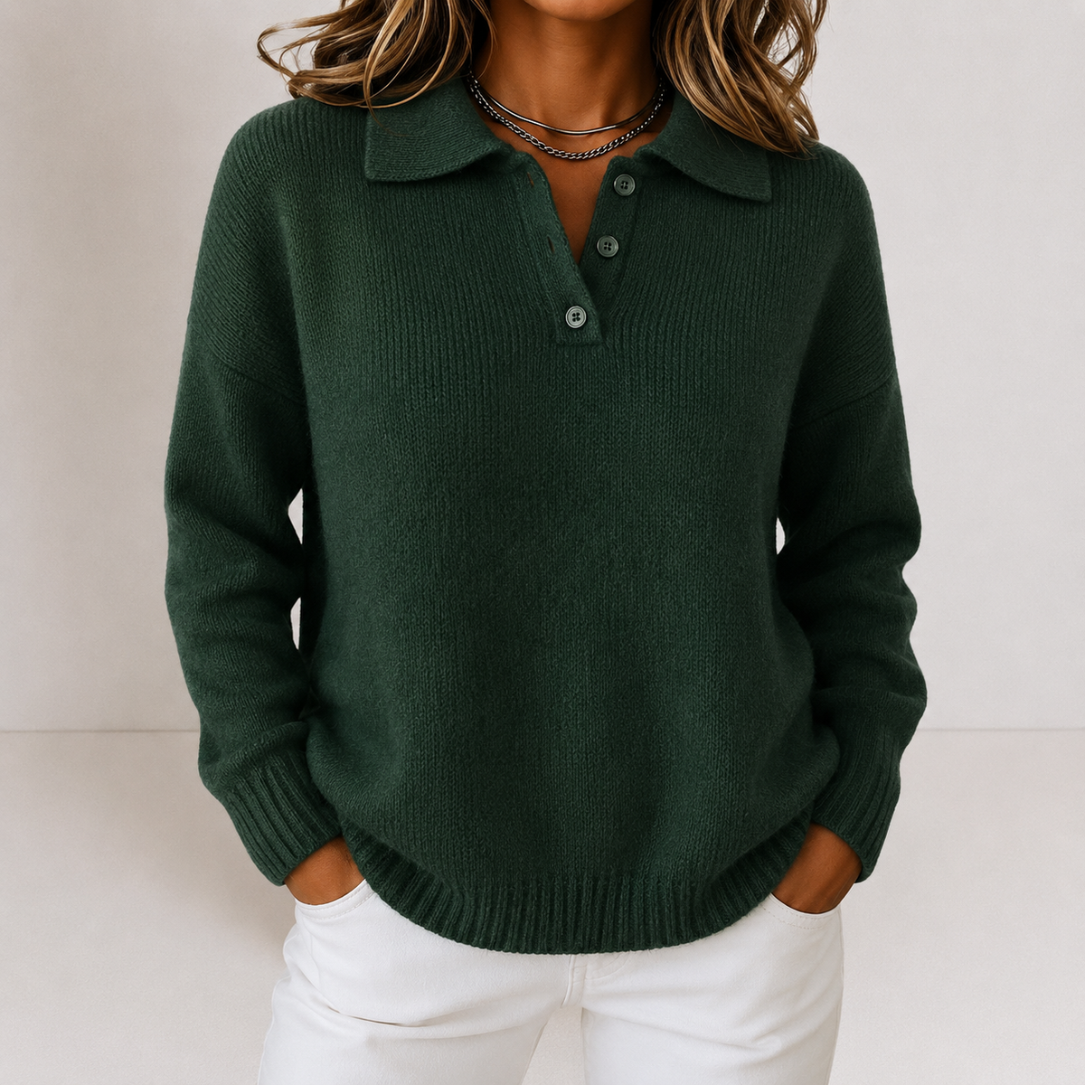 Dark green polo collar sweater with a button placket and ribbed cuffs and hem, worn with white pants.