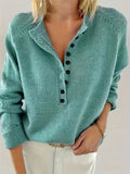 Woman wearing a sea green long-sleeve knit sweater with a stand collar, half-button placket with dark buttons and ribbed cuffs, paired with cream trousers._0
