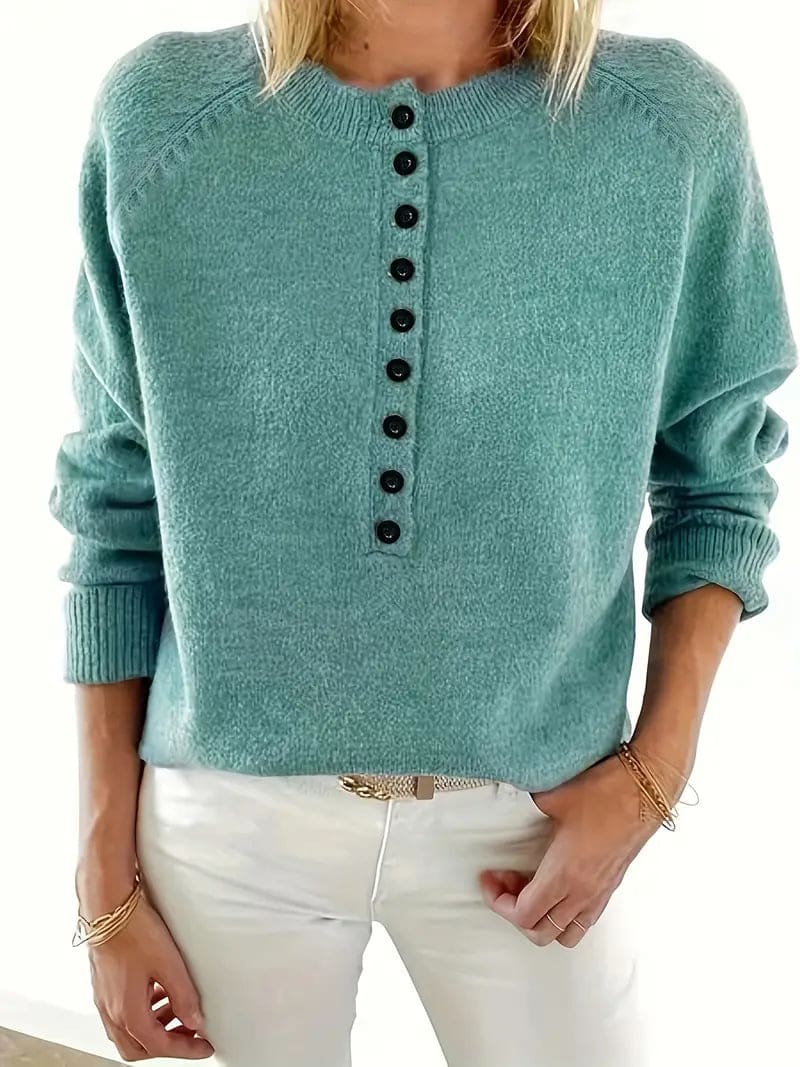 Woman wearing a sea green long-sleeve knit sweater with a stand collar, half-button placket with dark buttons and ribbed cuffs, paired with cream trousers._4