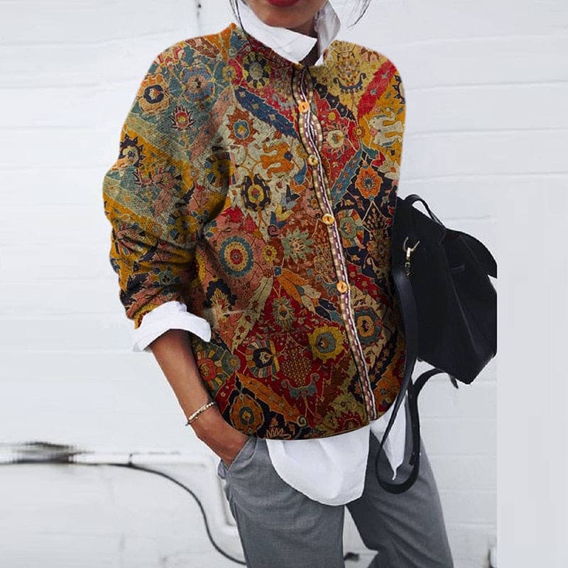 Woman wearing a long-sleeved button-front jacket with a colourful vintage floral print over a white shirt and grey trousers, holding a black backpack._0
