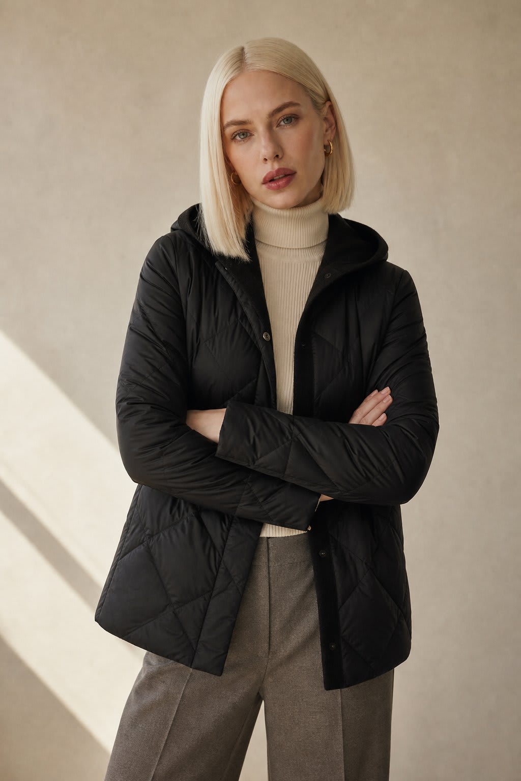 Woman wearing a quilted hooded jacket in a neutral tone with knit hood detail._2