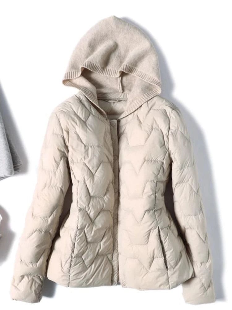 Woman wearing a quilted hooded jacket in a neutral tone with knit hood detail._4