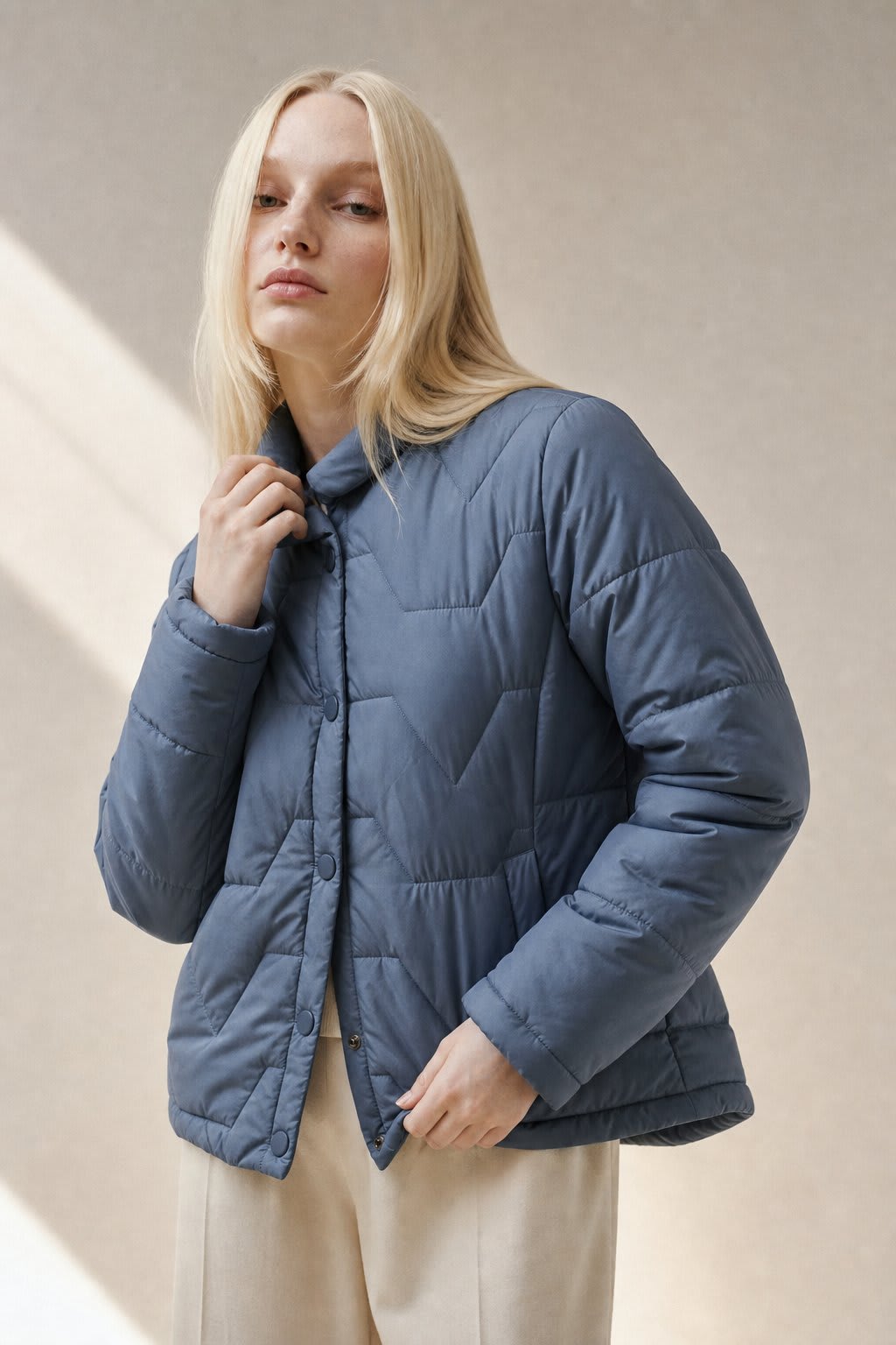 Woman wearing a quilted jacket with chevron stitching and snap button front closure._0