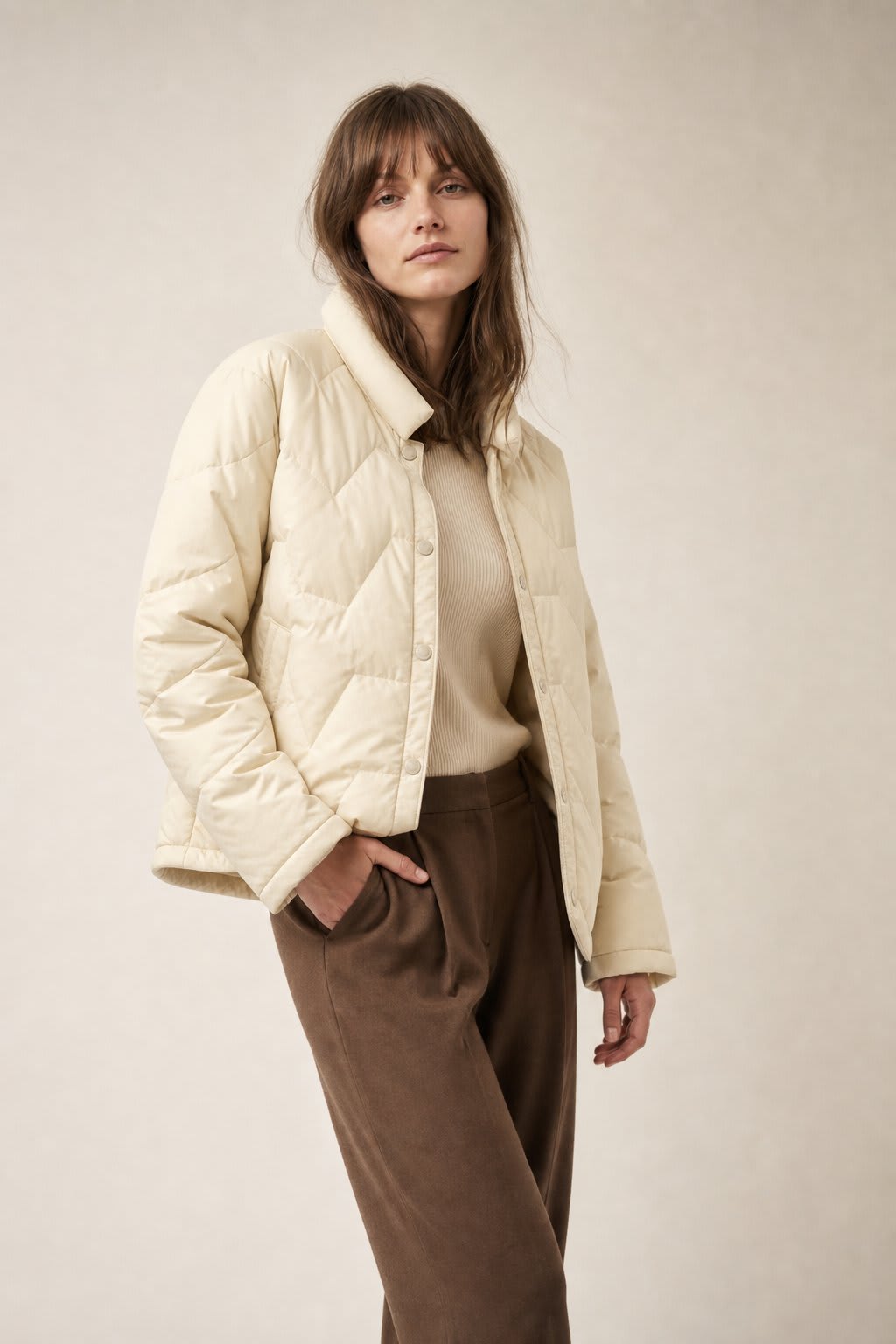 Woman wearing a quilted jacket with chevron stitching and snap button front closure._4