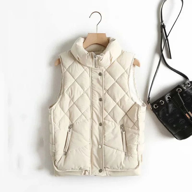 Model wearing a cream quilted vest with stand collar over a neutral sweater and brown trousers._10