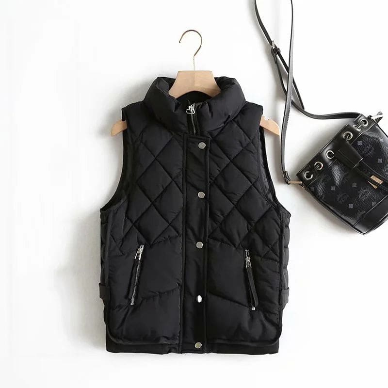 Model wearing a cream quilted vest with stand collar over a neutral sweater and brown trousers._12