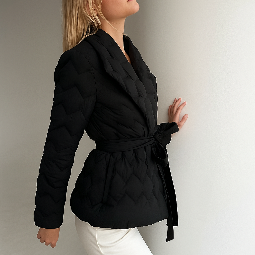 Woman wearing a quilted jacket with wrap front and tie belt in a warm neutral tone._36