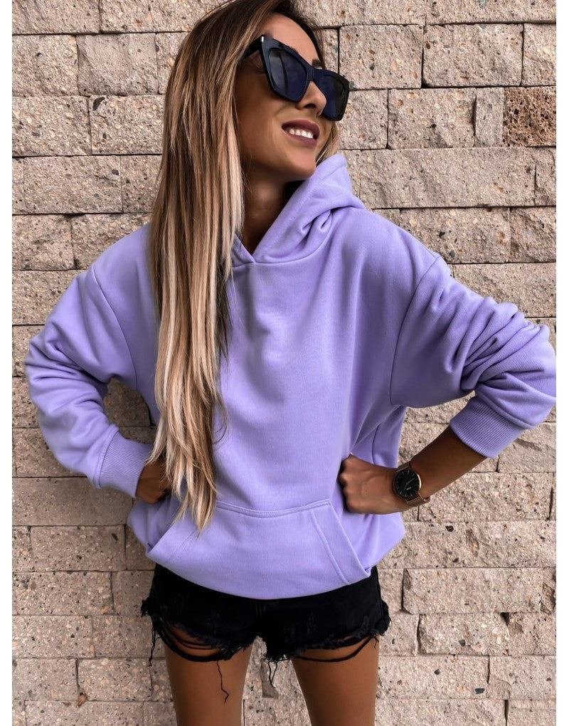 Lavender pullover hoodie shown from the front with hands on the hips, emphasizing its relaxed shape, hood, and front pocket.