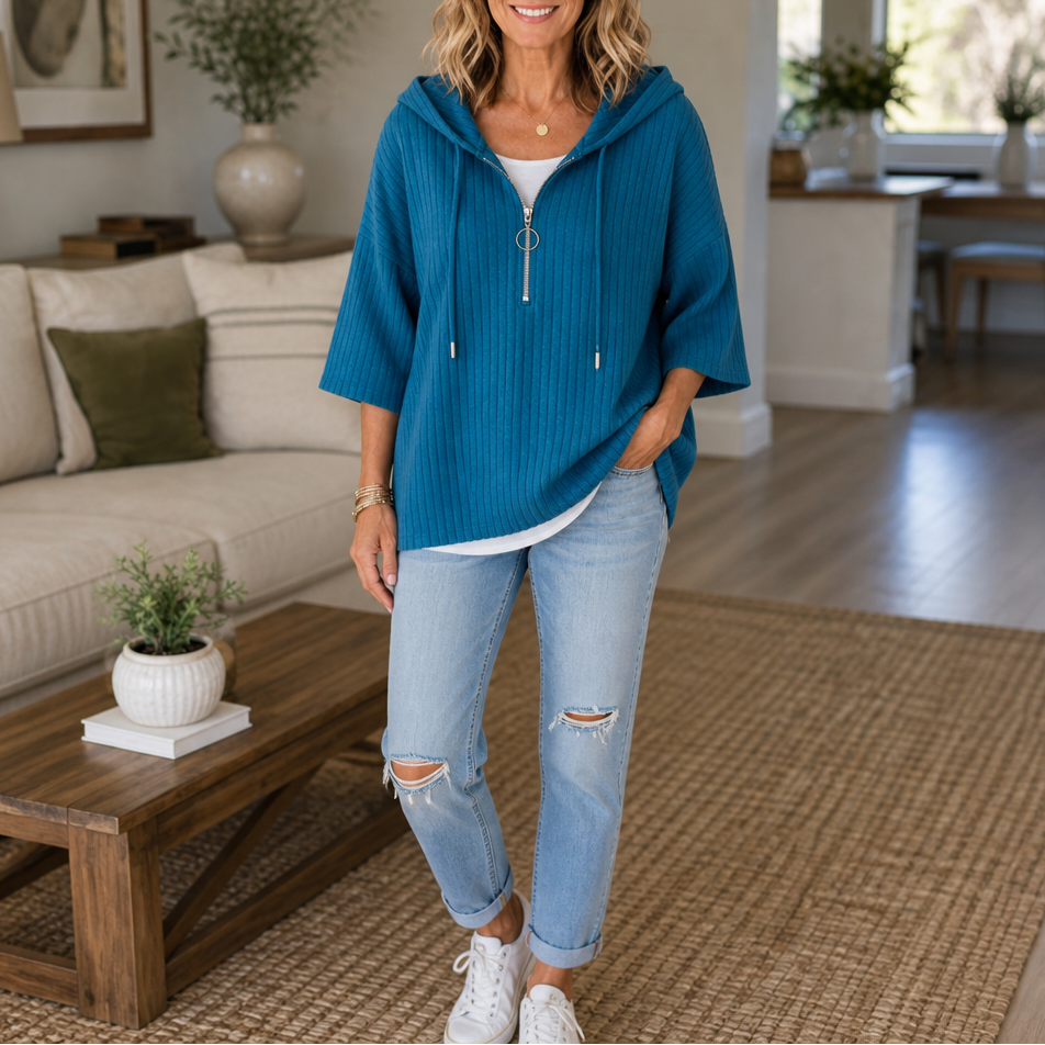 Teal blue ribbed hooded top with a half-zip neckline styled with cuffed jeans and sneakers.