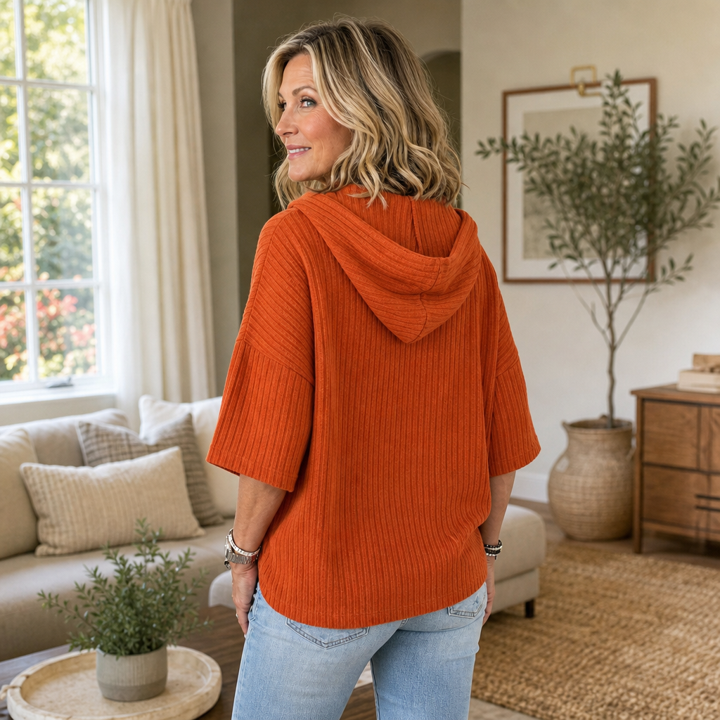 Back view of the orange ribbed hooded top showing the draped hood and loose shape.