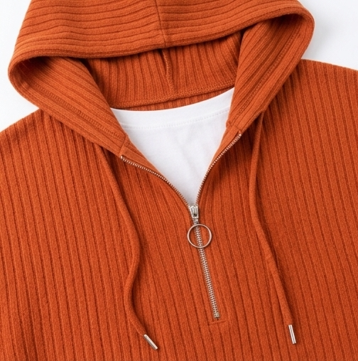 Close-up of the orange top’s hood and half-zip neckline with a ring pull and drawstrings.