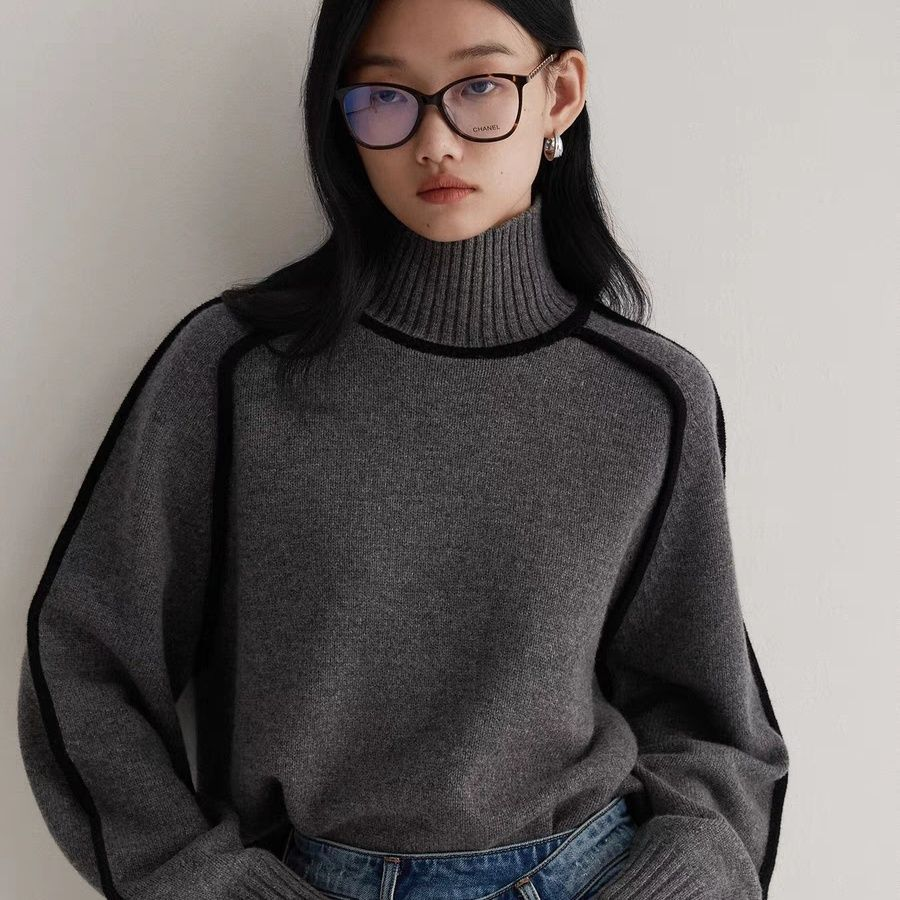 Woman wearing a beige turtleneck sweater with black contrast trim, styled with dark trousers and a black belt._4
