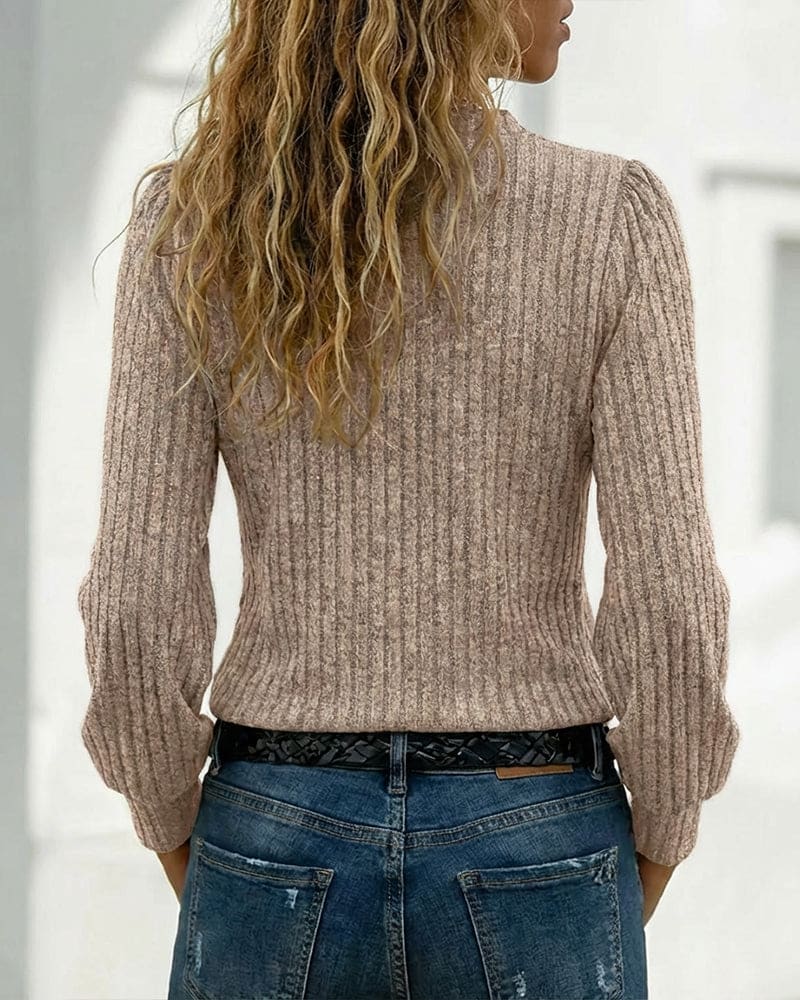 Beige ribbed long sleeve top with an asymmetric neckline, stand collar and four gold-tone buttons, worn with blue jeans._5