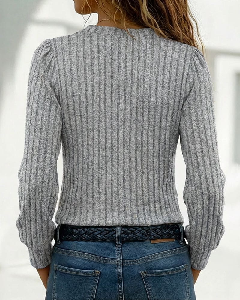 Beige ribbed long sleeve top with an asymmetric neckline, stand collar and four gold-tone buttons, worn with blue jeans._6
