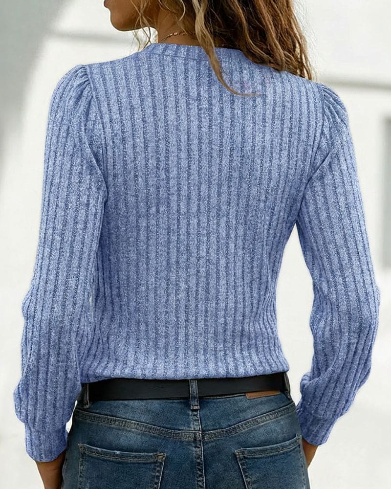 Beige ribbed long sleeve top with an asymmetric neckline, stand collar and four gold-tone buttons, worn with blue jeans._7