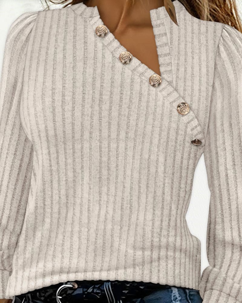 Beige ribbed long sleeve top with an asymmetric neckline, stand collar and four gold-tone buttons, worn with blue jeans._8