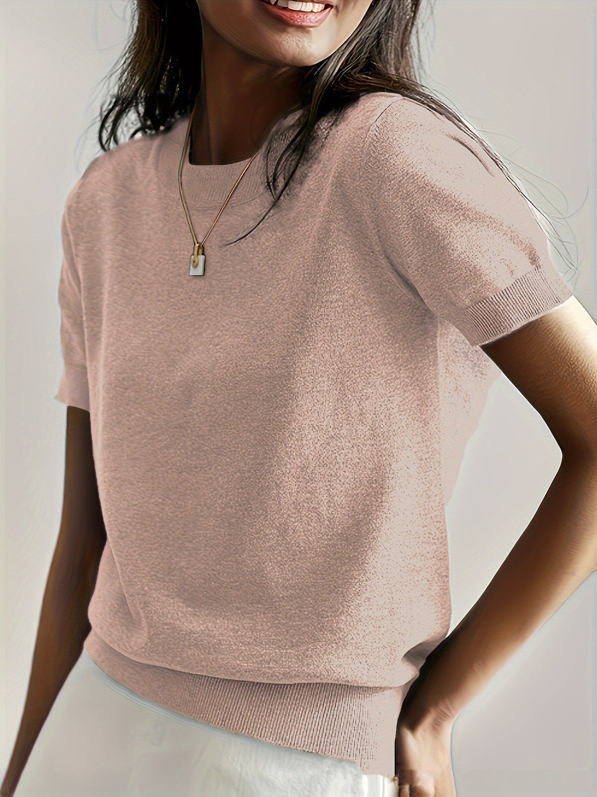Light blush short sleeve crew neck sweater shown close up with contrasting ribbed trim at the sleeves and hem.