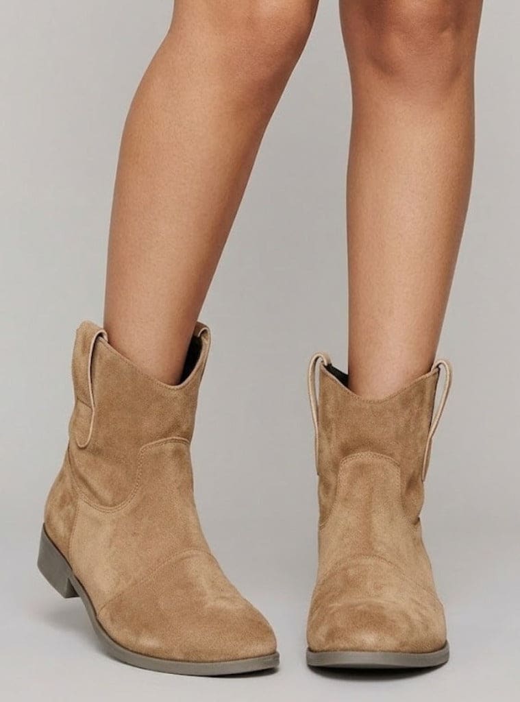 Close-up of a woman wearing tan slouchy ankle boots with pull tabs and a low block heel._0