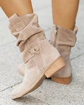 Light beige slouchy boots shown from the side with gathered shafts, buckle details, side zipper, and low block heels.