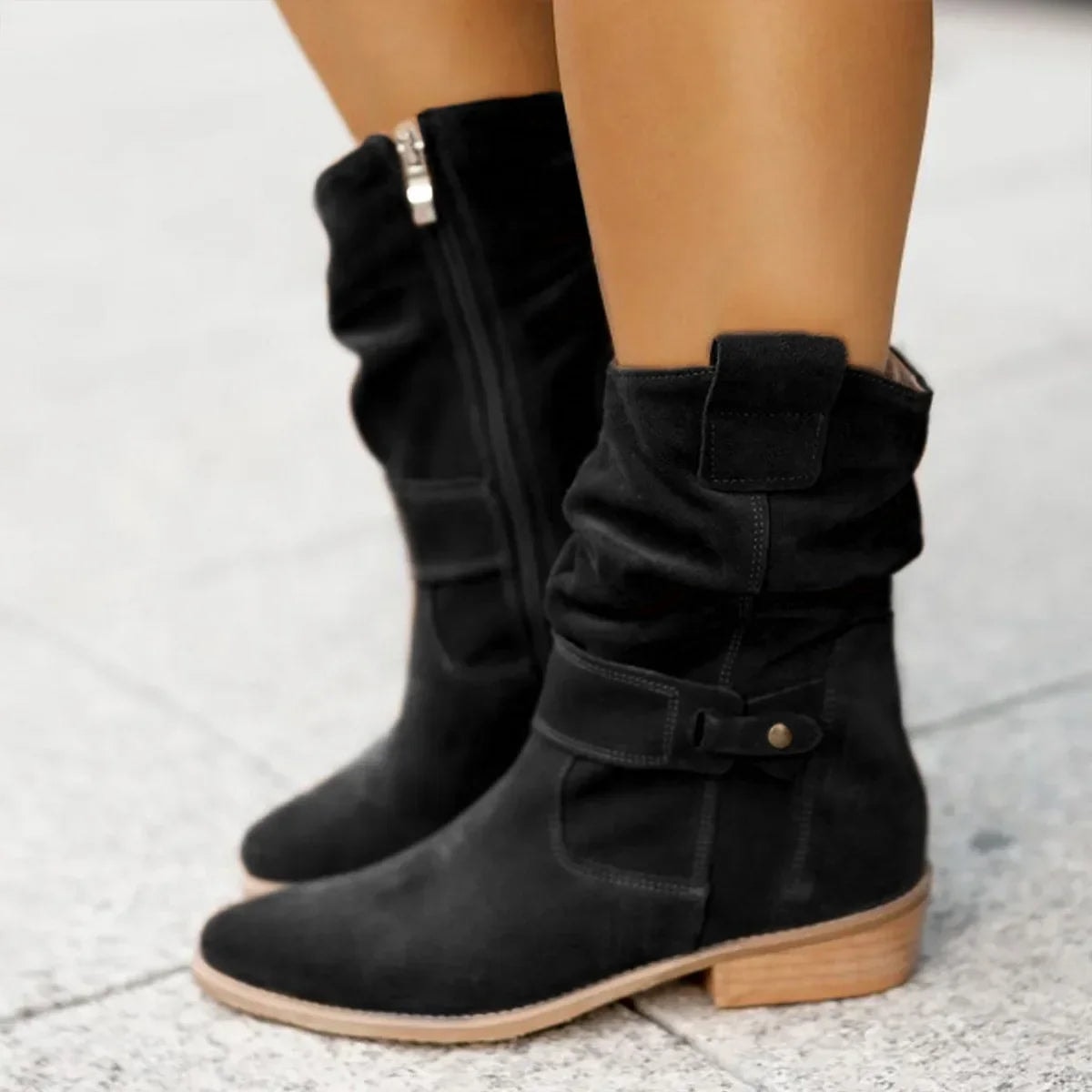 Black slouchy boots shown in a side-by-side standing view, featuring gathered shafts, ankle buckles, side zippers, and flat heels.