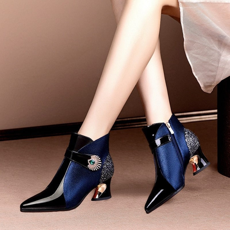 Navy sparkle-panel ankle boots shown in a close side view, emphasizing the glossy pointed toes, ankle zippers, and sculpted heels.