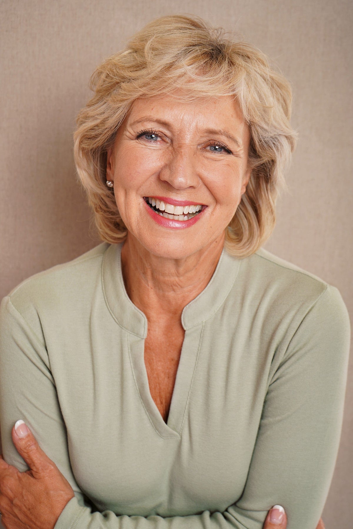 Woman wearing an olive green long sleeve top with a split stand-up neckline and black trousers._5