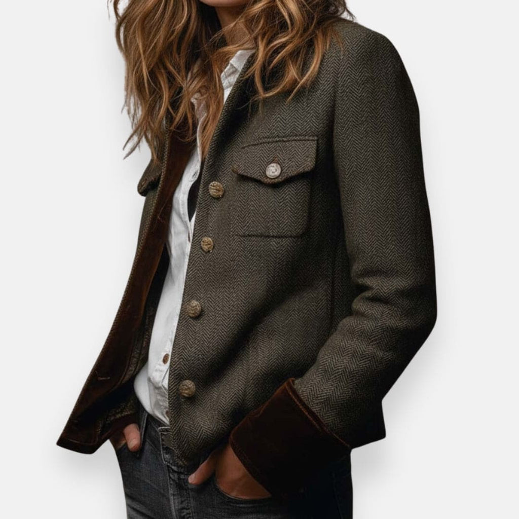 Woman wearing a structured herringbone jacket with contrast brown cuffs, chest pockets, and button-front closure, layered over a white shirt and jeans._2