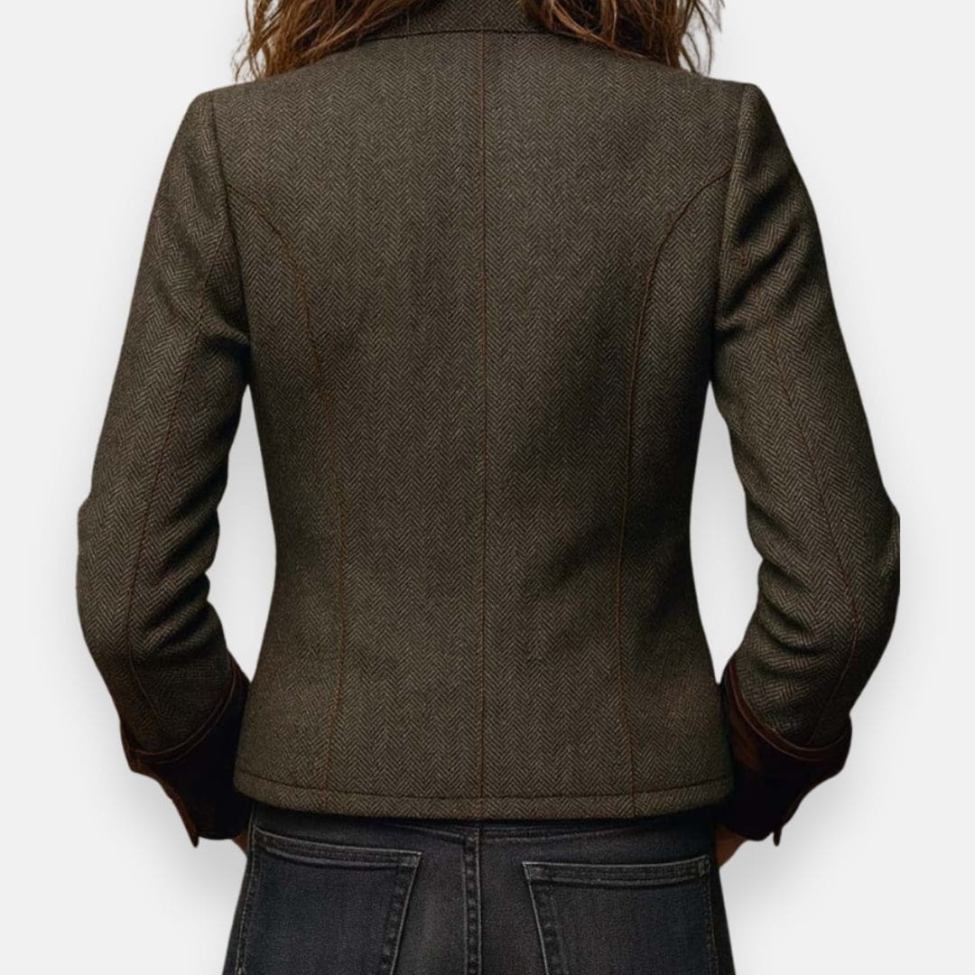 Woman wearing a structured herringbone jacket with contrast brown cuffs, chest pockets, and button-front closure, layered over a white shirt and jeans._3