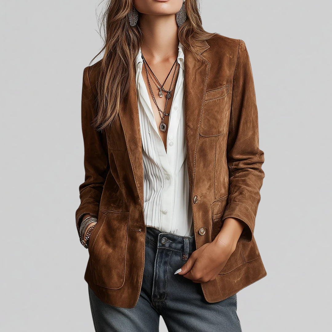 Woman wearing a structured brown blazer layered over a white button-down blouse with jeans and layered necklaces._0