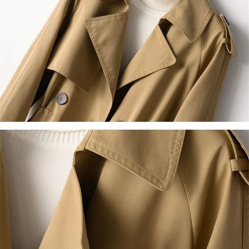 A double breasted trench coat with wide lapels, shoulder epaulets, and buckle cuff tabs is shown on a hanger._6