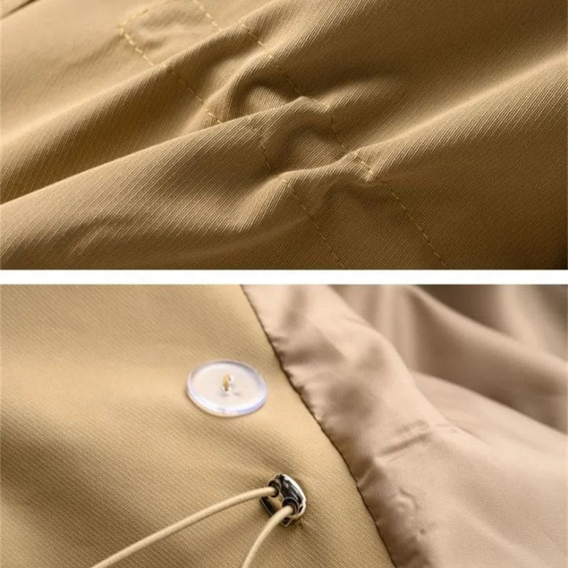 A double breasted trench coat with wide lapels, shoulder epaulets, and buckle cuff tabs is shown on a hanger._7