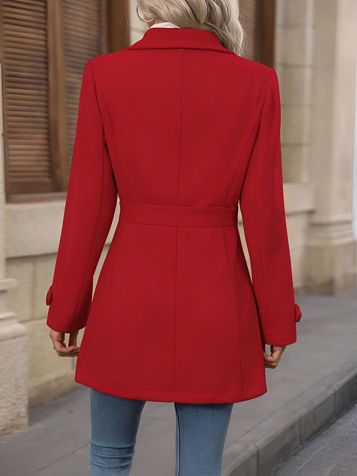 Woman wearing a tailored trench coat with notched lapel, double breasted button front, and tab details, styled over a white turtleneck and jeans._12