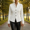 Woman wearing a textured blazer with notched lapels and three-button closure, styled with a collared shirt and trousers outdoors._0