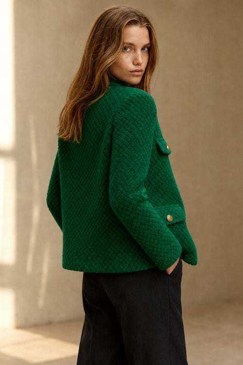 Woman wearing a textured short jacket with gold buttons in a tailored silhouette, viewed from behind._0