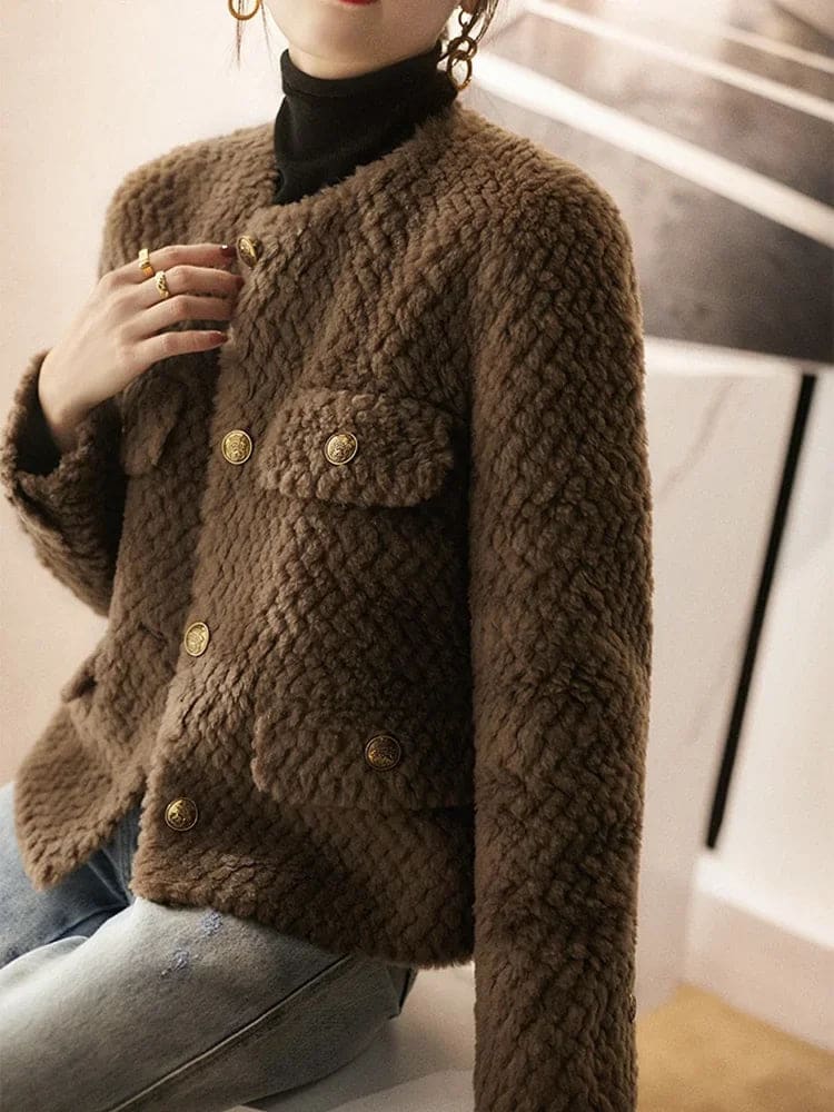 Woman wearing a textured short jacket with gold buttons in a tailored silhouette, viewed from behind._15