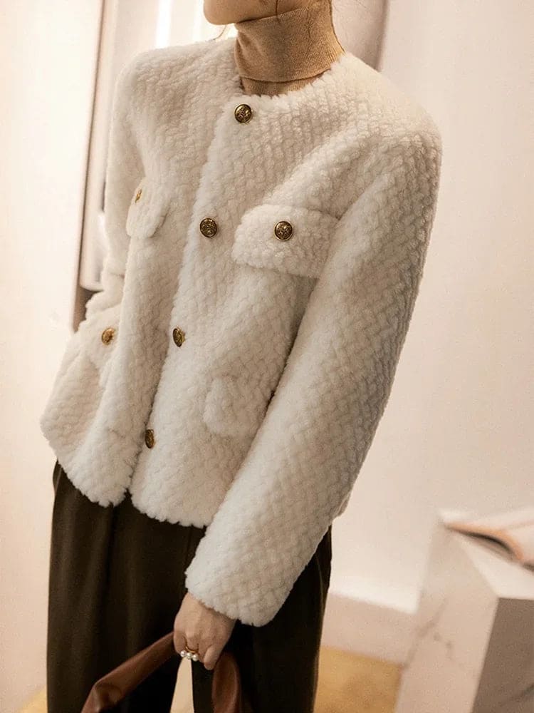Woman wearing a textured short jacket with gold buttons in a tailored silhouette, viewed from behind._17